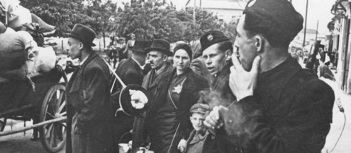 Slovak militia standing next to Jews, before the latter were deported from Slovakia along with their personal effects, 1942 Slovak militia standing next to Jews, before the latter were deported from Slovakia along with their personal effects, 1942