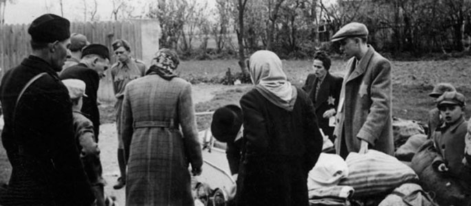 Slovak militia standing next to Jews, before the latter were deported from Slovakia along with their personal effects, 1942
