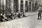 A Waffen SS soldier guarding Jews who had been apprehended hiding in underground bunkers during the Warsaw Ghetto uprising A Waffen SS soldier guarding Jews who had been apprehended hiding in underground bunkers during the Warsaw Ghetto uprising