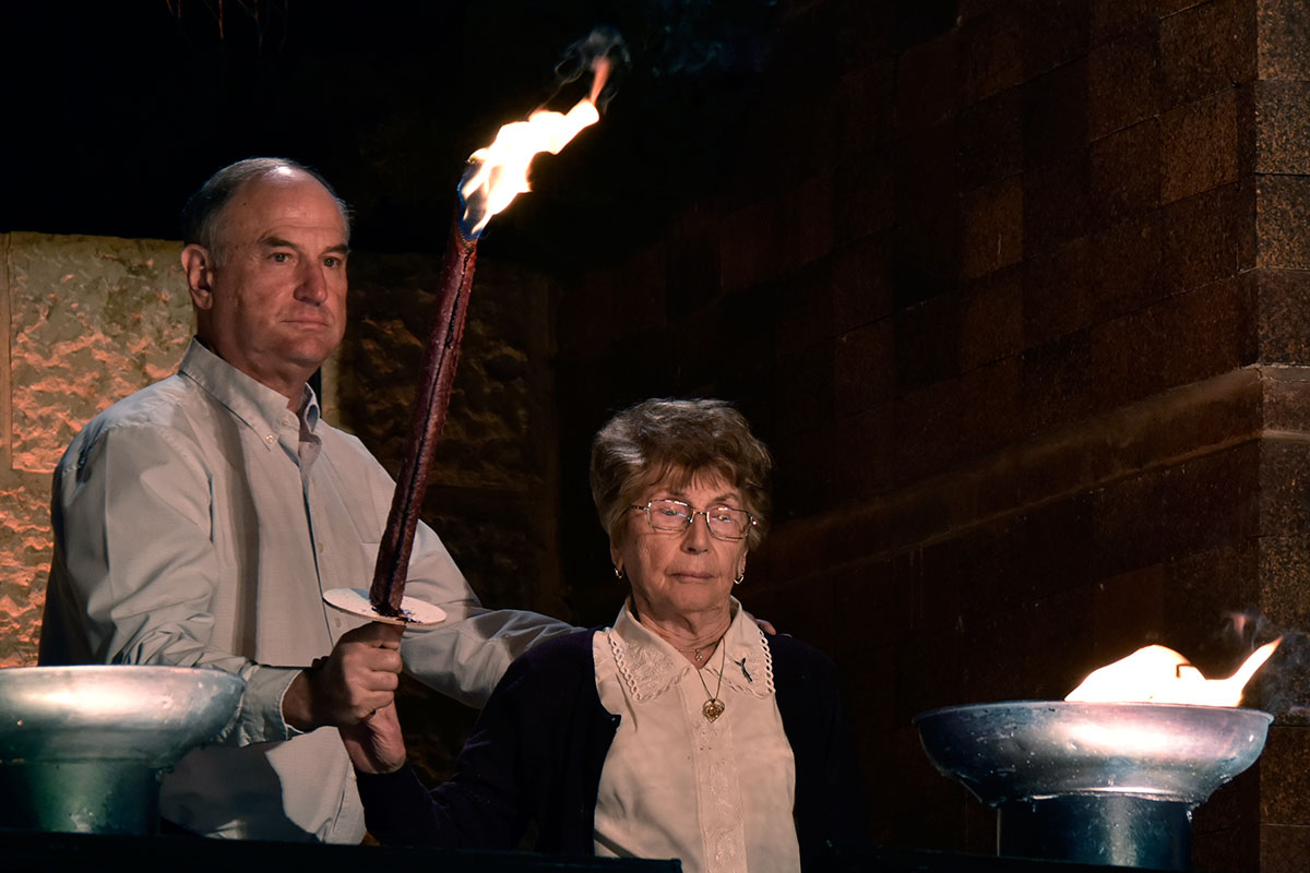 La sobreviviente del Holocausto Bela Eizenman encendiendo una de las seis antorchas durante la ceremonia
