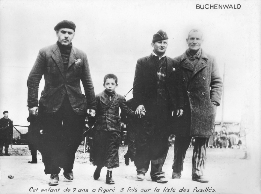 Un enfant encadré par des résistants de Buchenwald, à la libération du camp. Buchenwald, Allemagne, juin 1945
