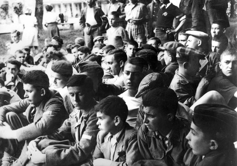 Les "enfants de Buchenwald" assis sur l'herbe, devant la maison d'enfants d'Ecouis, France, été 1945